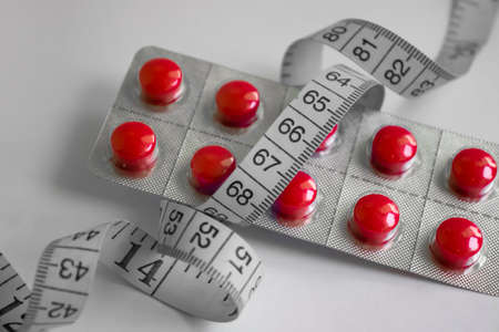Pills, centimeter tape on a light backgroundの写真素材