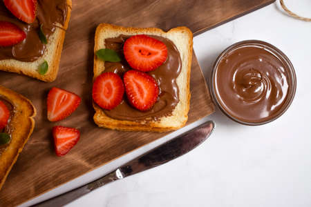 Bread with chocolate paste, strawberries on a light backgroundの写真素材