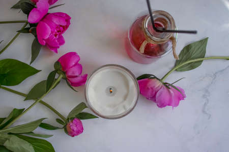 Perfume for home, candle, peony flower on a light backgroundの写真素材