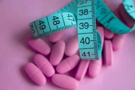 Measuring tape, pills on a colored background