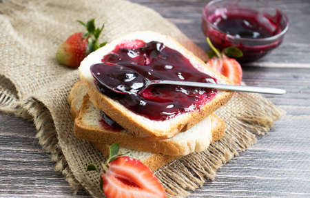 Strawberry jam, bread, fresh berry on a wooden backgroundの写真素材