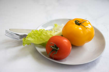 Tomato, lettuce leaf on a plate, diet conceptの写真素材