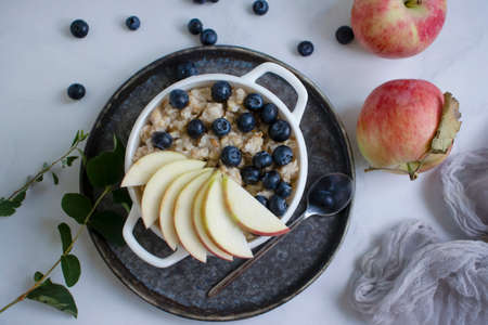 Oatmeal with fresh blueberries, apple, backgroundの写真素材
