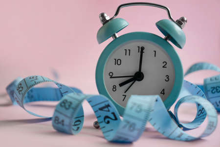 Alarm clock, measuring tape on a colored backgroundの写真素材