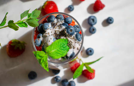 Yogurt, chia seeds, raspberries
, strawberries, blueberries, mint on a light background