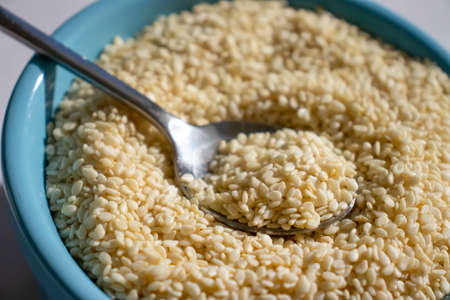 Sesame seeds spoon on old background