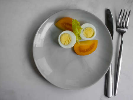 Boiled egg, tomato, lettuce on a diet plateの写真素材