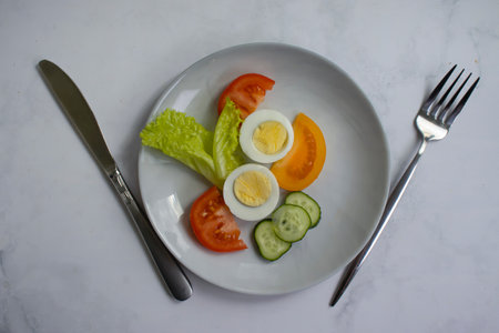 Boiled egg, tomato, lettuce on a diet plateの写真素材