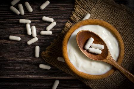 Plate with white yogurt, capsules on old background