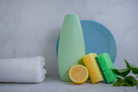 Bottle of dish detergent, lemon, sponge on a light backgroundの写真素材