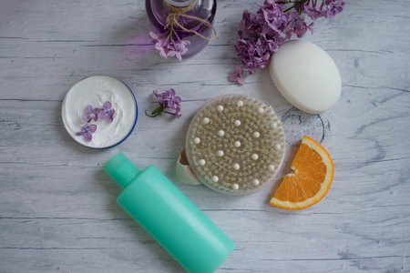 Massage brush, cream, lilac flower, orange on a light backgroundの写真素材