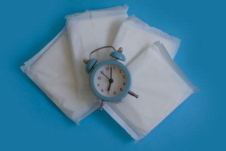 Sanitary pad, alarm clock on a colored backgroundの写真素材