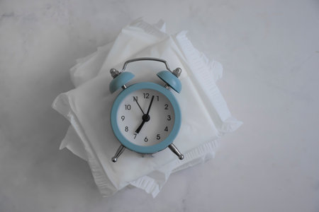 Sanitary pad, alarm clock on a colored backgroundの写真素材