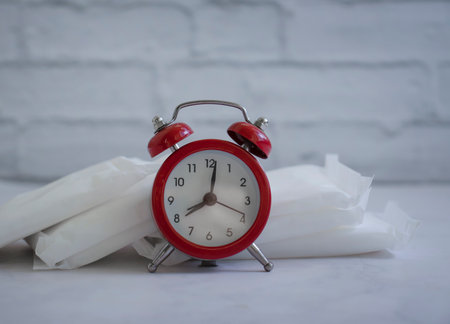 Sanitary pad, alarm clock on a colored backgroundの写真素材