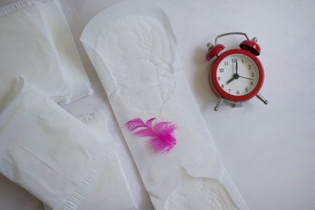 Sanitary pad, alarm clock on a colored backgroundの写真素材