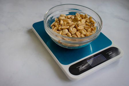 Electronic kitchen scales, peanuts on a light background