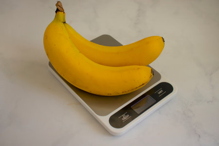 Fresh bananas, kitchen scales on a light backgroundの写真素材