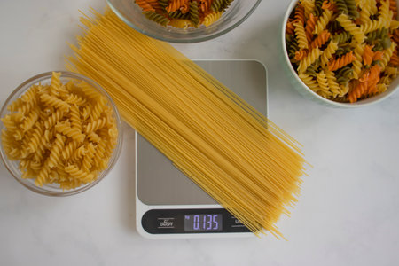 Dry pasta, kitchen scales on a light background