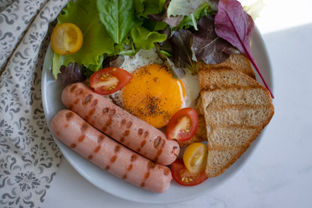 Fried egg with sausages, lettuce, tomato, toastの写真素材