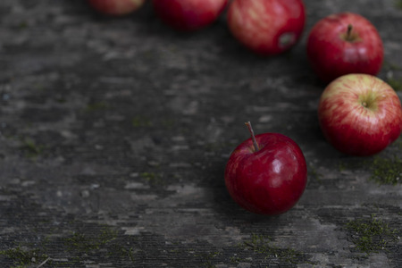 Red apples on an old wooden surface  covered with moss here and there. Red apples on an dark old wooden table.の写真素材