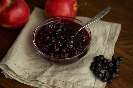 Home made black apple and apple confiture in a glass jar on a wooden background.の写真素材