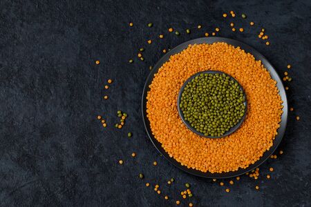 Beans on a dark background. Lentils and green mung bean in a flat plate. Healthy food for vegans. Horizontal position. Top view. Copy space.の写真素材