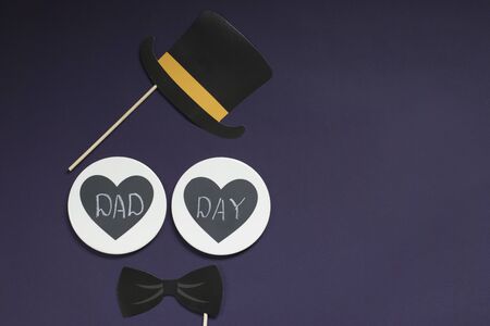 Happy father's day. On a violet background is a bow tie, a bowler hat, two hearts with the inscription father's day. Copy space.の写真素材