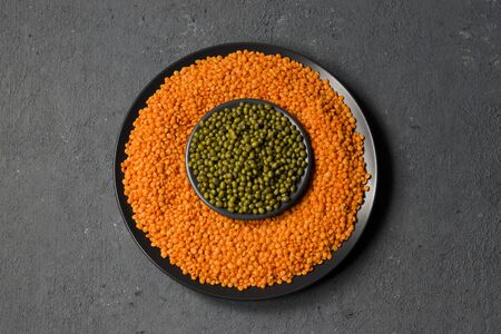 Beans on a gray background. Lentils and green mung bean in a flat plate. Healthy food for vegans. Top view. Horizontal position in the center.の写真素材