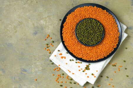 Beans on a dark background. Lentils and green mung bean in a plate on a cotton napkin. Healthy food for vegans. Horizontal position. Top view. Copy spaceの写真素材