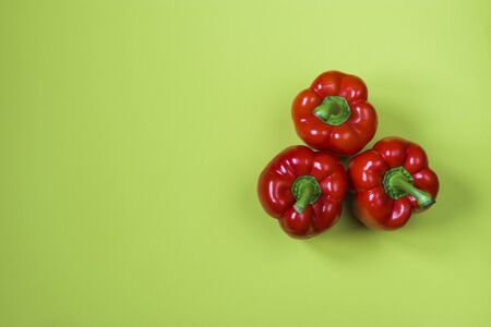 Fresh red bell peppers on a green background. Top view. Horizontal position. Copy space.の写真素材