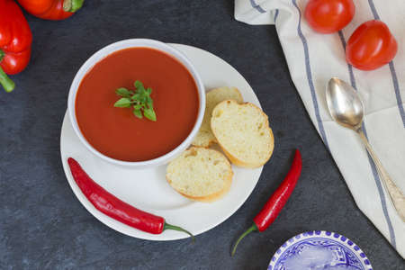 Summer diet cold gazpacho soup, tomatoes, peppers, cucumbers and greens on a white background top view. Vegetarian food. Ice for cooling.の写真素材