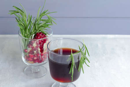 Pomegranate non-alcoholic cocktail with rosemary on a light background. Fruit grains in a glass. Natural healthy drink.の写真素材