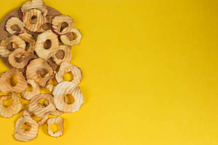 Natural apple chips on a yellow background. Healthy vegan vegetarian fruit snacks. Organic food for wellness. It's time to lose weight.の写真素材
