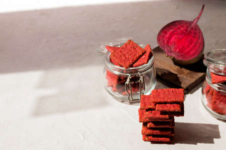 Natural crackers or beetroot cookies in glass jars on a light background. Healthy food concept for wellness. Copy space.の写真素材