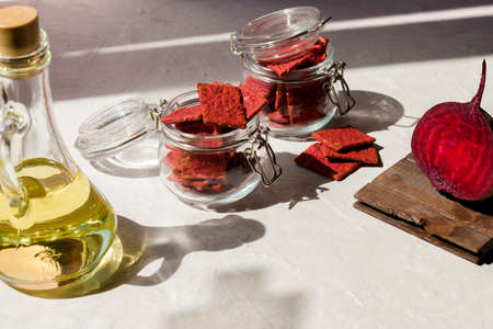Natural crackers or beetroot cookies in glass jars on white