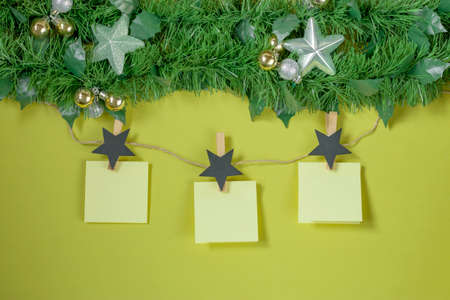 Creative christmas tree branch with new year toys and wish sheets or notice on green background....