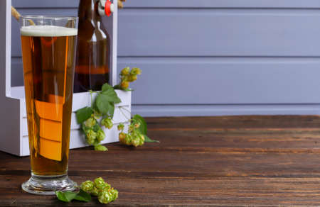 Home brewing. Make a light beer from natural ingredients. Still life with hops and beer on a wooden...
