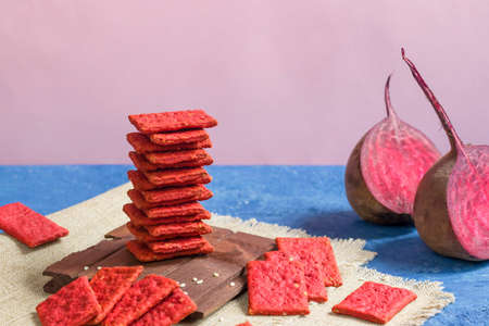 Beetroot natural crackers or cookies on a blue background. Healthy food concept for wellness. Diet foods.の写真素材