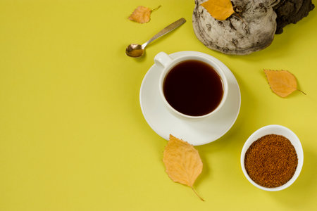 Healing tea, coffee and pieces of birch chaga in a white cup on a yellow background. Naturopathy. Alternative medicine. A trendy superfood for immunity. Natural antioxidant. Top view. Copy space.の写真素材