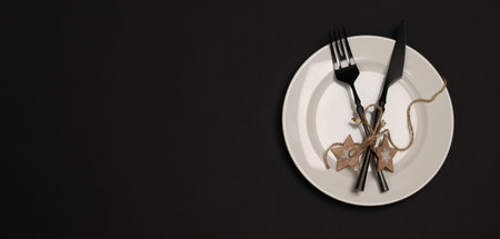 Table setting New Year and Christmas. White plate, black cutlery on a black banner background. Modern and elegant. Copy space. flat lay.の写真素材