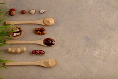 Concept for natural and vegetarian products. Butter, nut paste in wooden spoons with ingredients on...