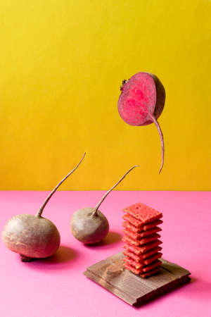 Natural crackers or beetroot cookies on double yellow and pink background. Beets on a wooden board....