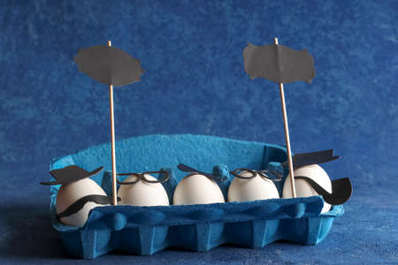 White egg with glasses on a black plate, a table knife and a fork on a green background. Easter holiday creative concept. Flat lay. Copy space.の写真素材