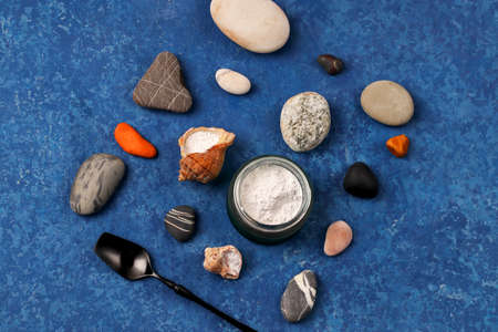 Hydrolyzed marine collagen powder in a glass jar among stones on a blue background. Natural...