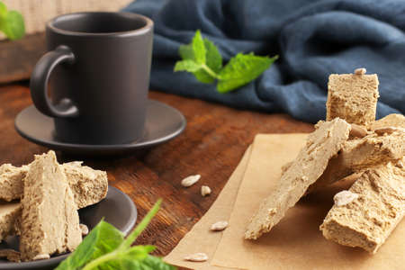Halva with pistachios on parchment paper on a wooden background. Natural vegan product. Turkish,...