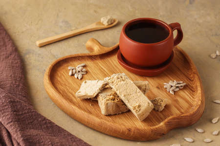 Halva with pistachios on parchment paper on a wooden background. Natural vegan product. Turkish,...