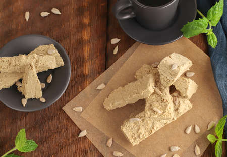 Sunflower halva on parchment paper on a wooden background with a blue napkin. Eastern sweets. Natural vegan product. Rustic style. Top view. Flat layの写真素材
