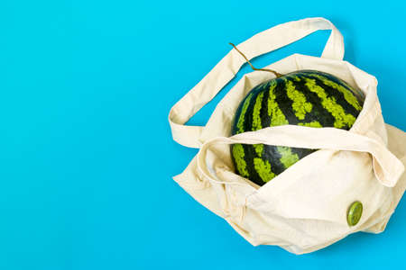 Detox in a reusable shopping bag. Watermelon in eco packaging on a blue background. Zero waste...