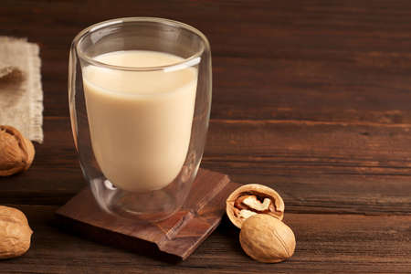 Natural breakfast. In a glass glass, gluten-free walnut milk on a wooden background. Organic vegetarian drink. Rustic style. Health concept. Copy spaceの写真素材