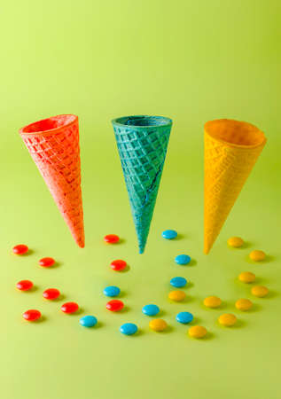 Colored waffle cones for ice cream and sweets on a light background. Summer creative concept. Levitation. Vertical position.の写真素材
